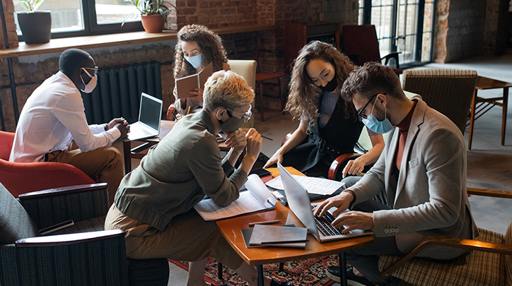 Masked employees working through a project